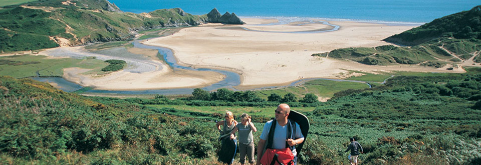 Walkers at Three Cliffs Bay on the Gower Peninsula in Wales